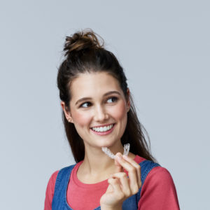 Smiling woman holding clear aligners
